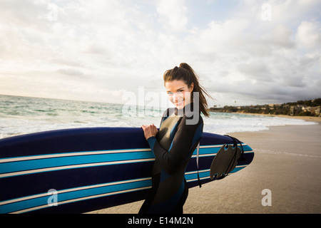 Caucasian surfer carrying board in surf Banque D'Images
