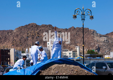 Enfants jouant sur un tas de terre couverte d'une bâche bleue, Muscat, Oman Banque D'Images