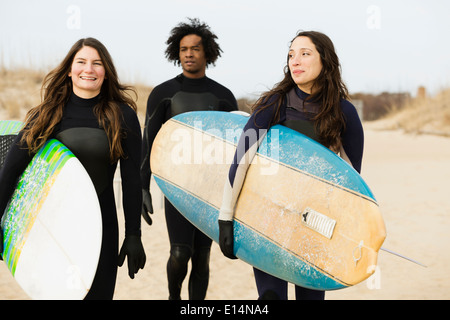 Surfers carrying boards on beach Banque D'Images