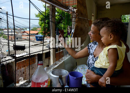 Femme, 38 ans, avec son fils, 1 ans, en regardant par la fenêtre de sa maison dans la favela Senador Camara, Rio de Janeiro Banque D'Images