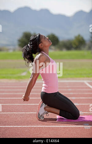 Jeune femme sportive sur une piste de course, stretching arms Banque D'Images