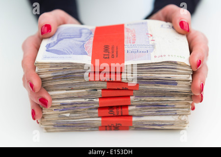 Une femme tenant £1000 paquets de la livre sterling. Banque D'Images