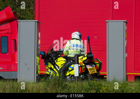 Moto de police à aire sur deux voies avec Royal Mail chariot passant Banque D'Images