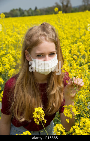 Portrait d'une adolescente dans un champ de colza portant un masque de visage allergy sufferer Banque D'Images