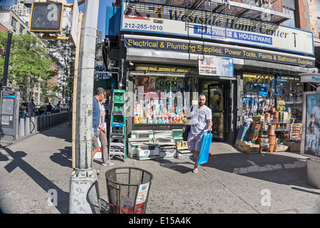 Scène à l'extérieur de la maison du coin de la boutique avec des marchandises empilées sur le trottoir dans le quartier Hell's Kitchen à Manhattan Banque D'Images