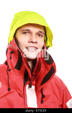 Jeune homme portant un marin étanche rouge veste vent et capot jaune isolé sur blanc. Bateau à voile de croisière. Studio shot. Banque D'Images