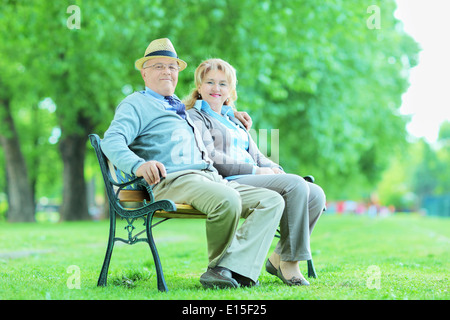 Vieux couple relaxing in park assis sur banc en bois Banque D'Images