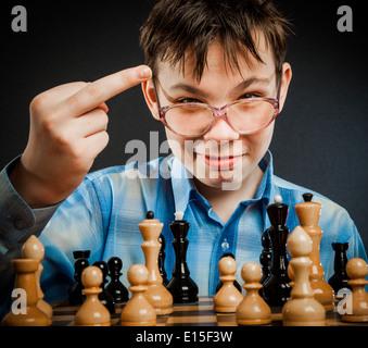 Wunderkind jouer aux échecs. Funny boy nerd. Montre le doigt du milieu à l'adversaire. Banque D'Images