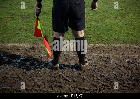 Un assistant de l'arbitre les jambes du couvert de boue au cours de la ville de Belper le match contre FC Gresley, Belper, Derbyshire. Banque D'Images