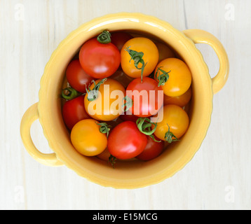 Tomates cerises jaunes et rouges dans le beurre plat à oreilles jaunes sur un fond blanc rustique coup de frais généraux Banque D'Images