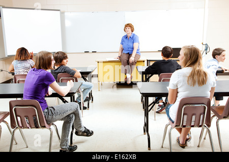 Enseignant assise sur son bureau, l'enseignement d'une classe d'étudiants adolescents. Banque D'Images