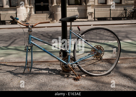 Old rusty location manquant de perte ou vol des roues avant, attaché à un poste de Rue, Manhattan NYC Banque D'Images