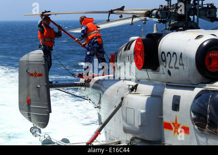 Mer de Chine orientale. 24 mai, 2014. Des soldats de la marine chinoise travailler sur un hélicoptère avant de l'envoyer dans le hangar du destroyer lance-missiles Qingdao en Chine au cours de l'exercice naval conjoint sino-russe sur la mer de Chine orientale, le 24 mai 2014. L 'exercice de trois jours de mer commune-2014' s'est achevée avec succès le samedi. Les marines chinoise et russe ont organisé des exercices, y compris des exercices d'escorte, et l'exercice d'identification d'aéronef mixte de défense aérienne et maritime des exercices d'agression. Credit : Zha Chunming/Xinhua/Alamy Live News Banque D'Images