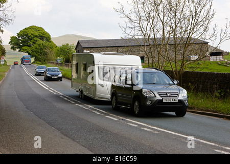 Les voitures d'attente derrière remorquage voiture caravane sur route A6 dans la région de Cumbria uk Banque D'Images