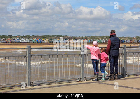 Southwold, Suffolk, Angleterre, Royaume-Uni. 24 mai 2014. Il s'agissait d'une lumineuse journée sur la côte du Suffolk au début de la Banque week-end de vacances. Une famille Profitez de la vue sur le front de mer et l'cabines colorées de l'extrémité de la jetée. Banque D'Images