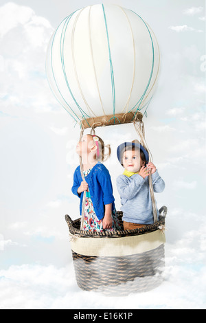 Petite fille et petit garçon (2-3, 12-23 mois) dans l'air chaud ballon flottant dans les nuages Banque D'Images