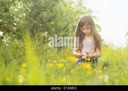 Girl (6-7) sitting on grass Banque D'Images