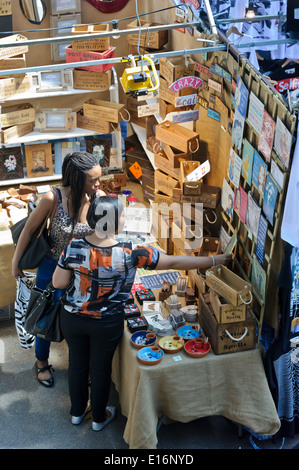 Deux jeunes femmes à la recherche à un article à la vente à l'ancien marché couvert de Spitalfields, Londres, Angleterre, Royaume-Uni. Banque D'Images