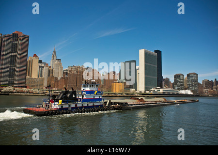 Tugboat pushing barges de gravier sur New York City's East River, Chrysler Building et bâtiment de l'Organisation des Nations Unies en arrière-plan Banque D'Images