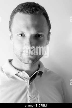 Young Caucasian Man closeup portrait noir et blanc au-dessus du mur gris Banque D'Images