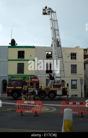 Hastings Marine Parade, les pompiers examiner grillee coquille de terrasse de maisons détruit par le feu le 25 mai 2014 Banque D'Images