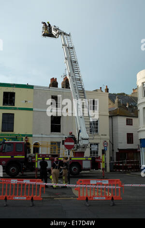 Hastings Marine Parade, les pompiers examiner grillee coquille de terrasse de maisons détruit par le feu le 25 mai 2014 Banque D'Images