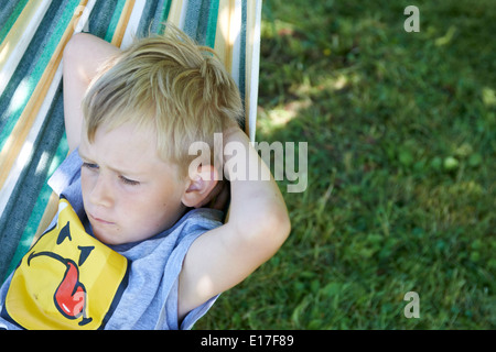 Jeune enfant garçon blond se reposant dans un hamac l'heure d'été Banque D'Images