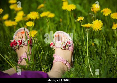 Young Girl lying on grass au milieu des pissenlits Banque D'Images