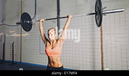 La jeune femme à l'haltérophilie gym crossfit. Mettre en place des poids lourds de levage modèle féminin au sport. Banque D'Images