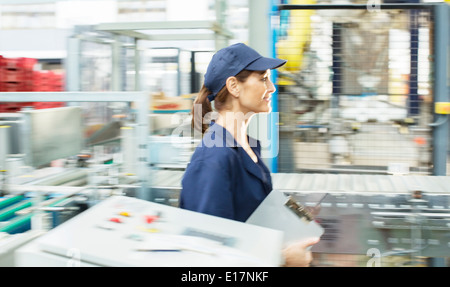 Presse-papiers avec des travailleurs pour les usines de transformation des aliments en marche Banque D'Images