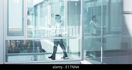 Businessman talking on cell phone in office corridor Banque D'Images