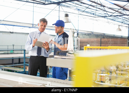 Superviseur et travailleur avec presse-papiers à l'usine de transformation des aliments Banque D'Images