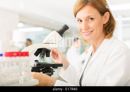 Portrait of smiling scientist using microscope in laboratory Banque D'Images