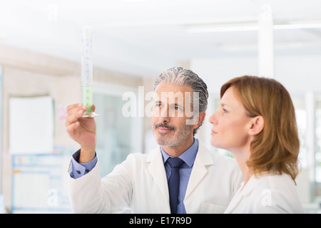 Les scientifiques examinant un liquide vert dans le tube. Banque D'Images