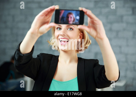 Jeune femme faisant rire une photo de son smartphone in office Banque D'Images