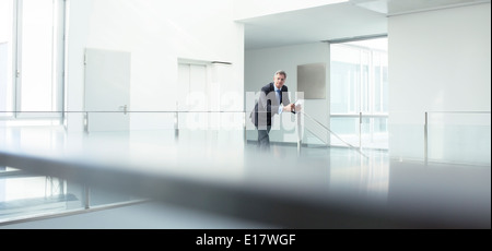 Businessman standing at railing in office Banque D'Images