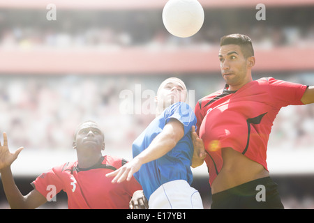 Joueurs de football de sauter sur le terrain de balle Banque D'Images