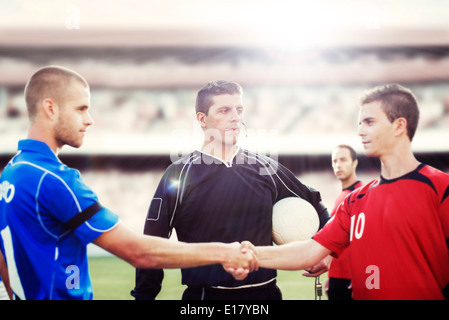 Joueurs de football shaking hands on field Banque D'Images