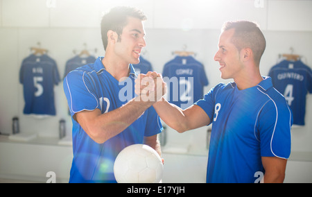 Joueurs de football shaking hands in locker room Banque D'Images
