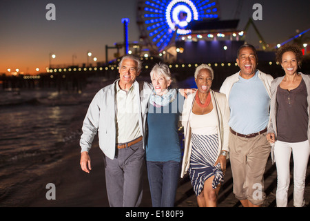 Senior friends walking on beach at night Banque D'Images