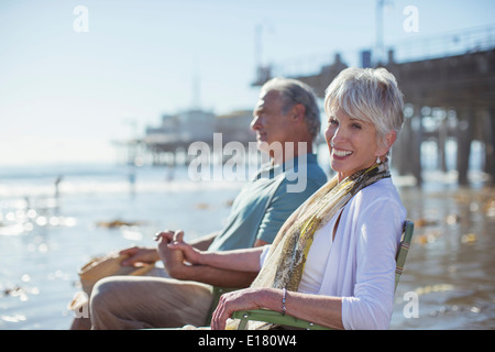 Portrait of senior couple relaxing in lawn chairs on beach Banque D'Images
