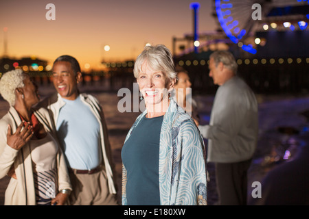 Portrait of senior woman enthousiaste avec des amis sur la plage au soir Banque D'Images