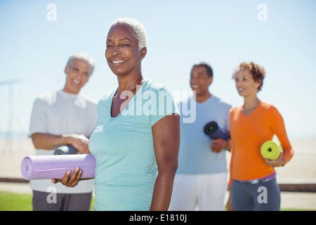 Portrait of smiling senior woman avec tapis de yoga in park Banque D'Images