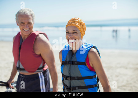 Couple enthousiaste dans les gilets de sauvetage sur plage Banque D'Images