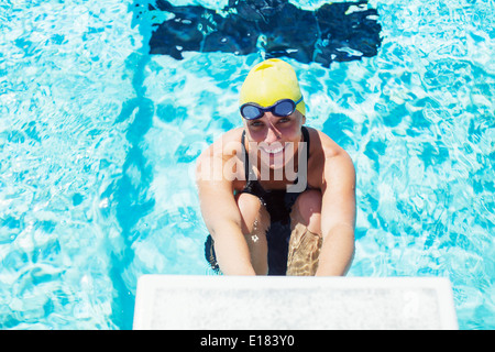 Portrait of smiling swimmer au bloc de départ Banque D'Images