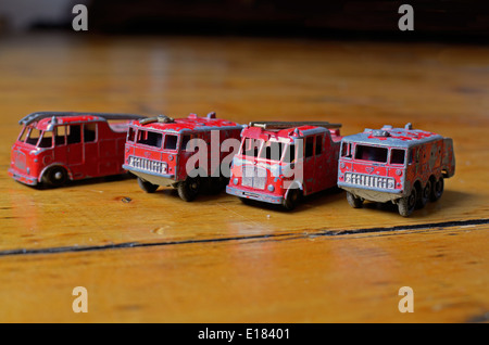 Quatre camions de pompiers jouet Matchbox alignés dans une rangée sur un sol en bois Banque D'Images