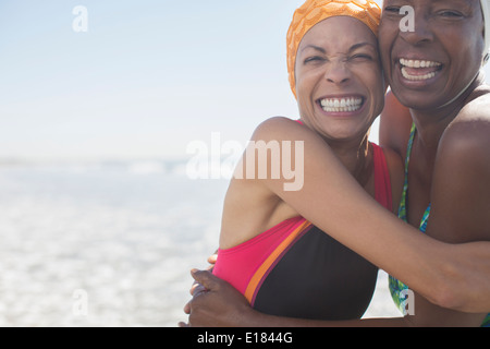 Les femmes enthousiastes hugging on beach Banque D'Images