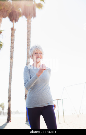 Senior woman power walking on beach boardwalk Banque D'Images