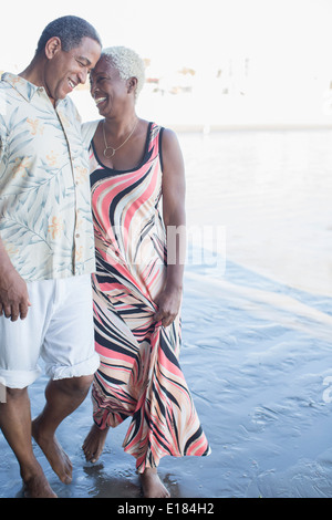 Senior couple marche pieds nus sur la plage Banque D'Images