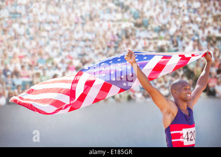 Athlétisme holding American flag in stadium Banque D'Images
